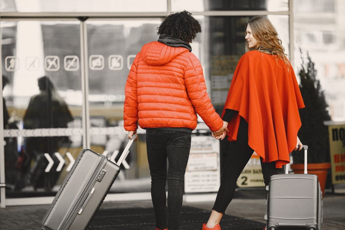 Couple walking into an airport terminal with suitcases, ready for a holiday departure