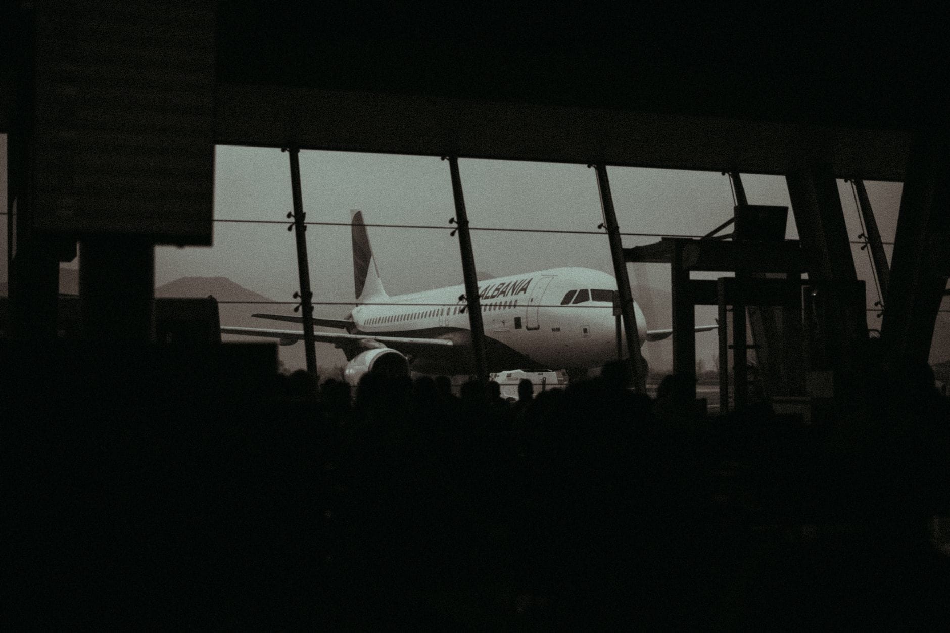 Silhouette of an airplane and waiting passengers inside an airport terminal at dusk
