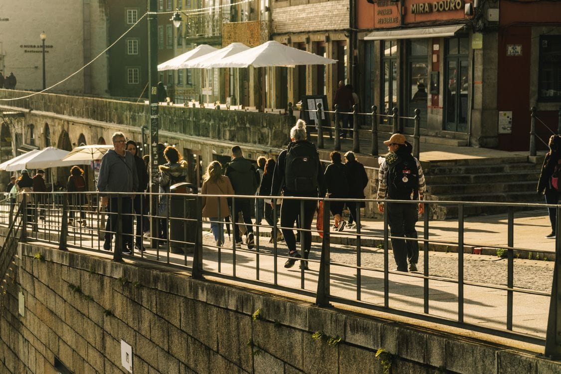 People crossing the Dom Luís I iron bridge over the Douro River with Porto on one side and Vila Nova de Gaia on the other