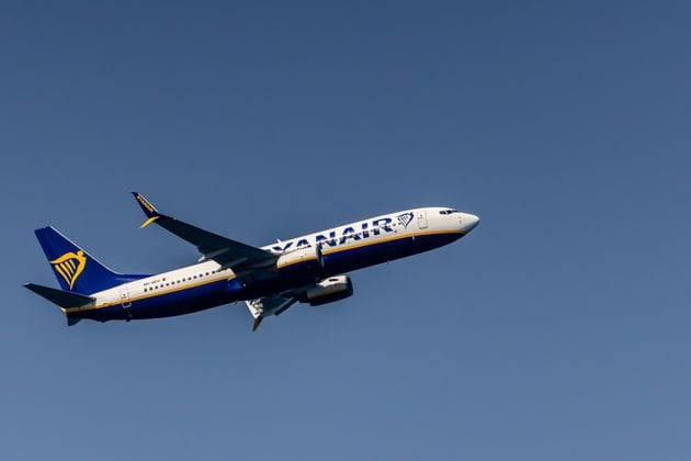 Ryanair aircraft flying high against a clear blue sky
