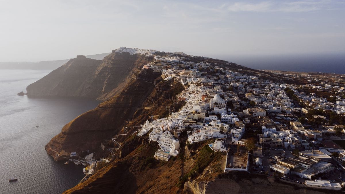 Aerial view of a clifftop Santorini town above the caldera at golden hour