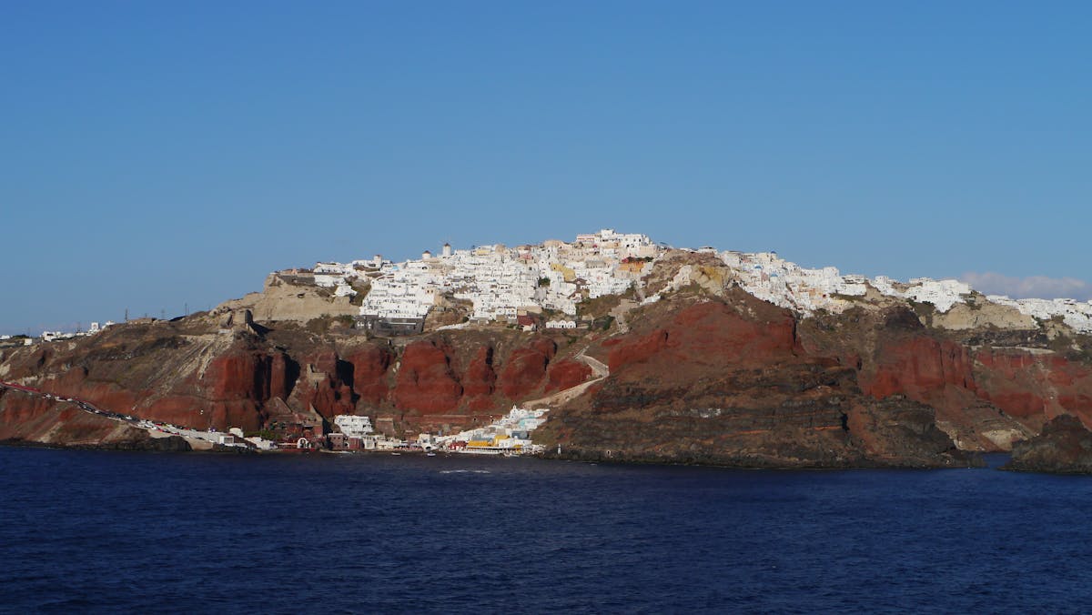 Oia perched on Santorini's red volcanic cliffs above Ammoudi Bay
