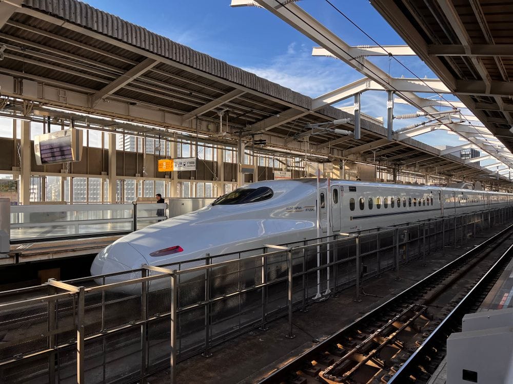 Shinkansen bullet train at Osaka station platform with blue sky