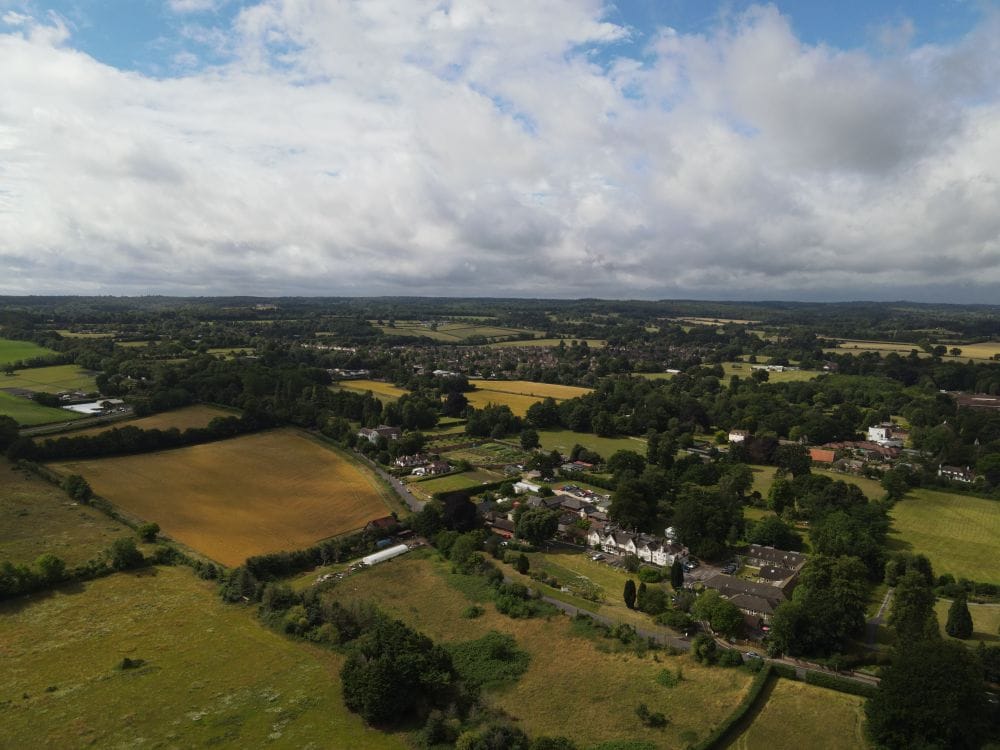 Aerial view of Surrey Hills countryside with green fields and blue sky, Box Hill is a day trip within an hour of London