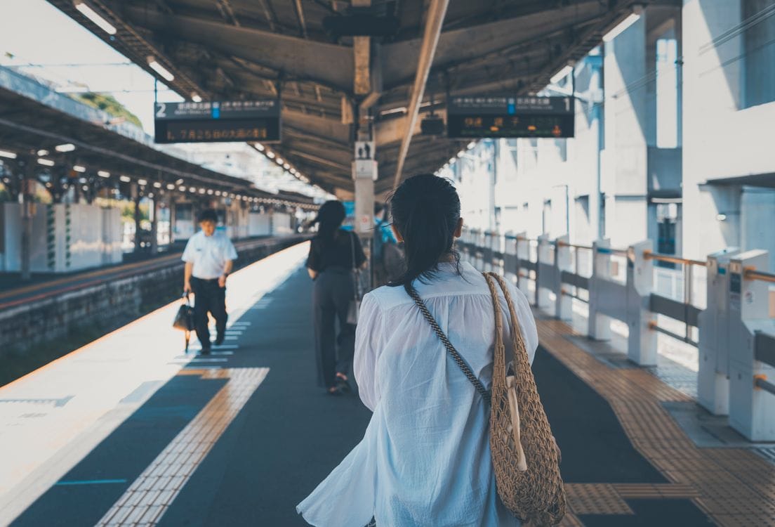 Commuters at a busy Tokyo train station with crowds on platforms and escalators