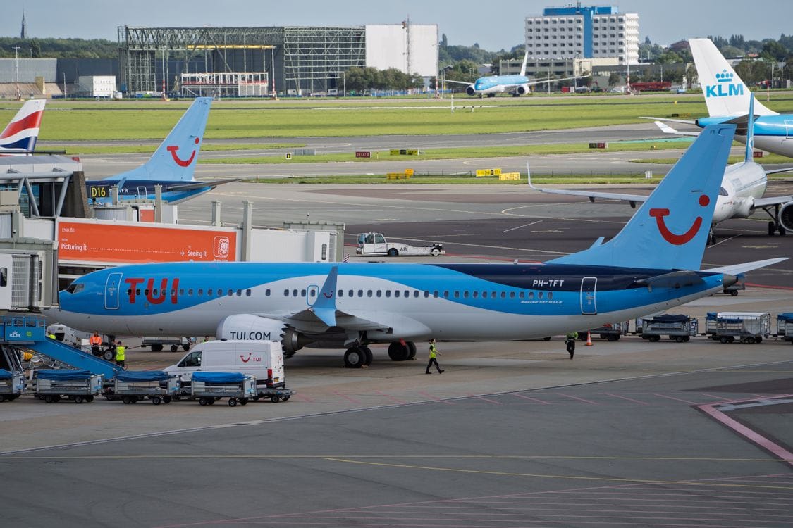 TUI Boeing 737 aircraft at airport terminal gate with ground crew and service vehicles visible