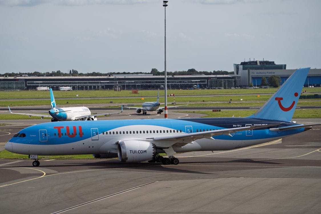 TUI Boeing 787 Dreamliner parked at an airport terminal with runway view