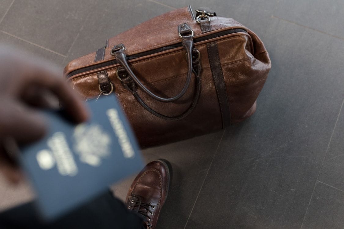 Brown leather travel bag with passport at airport, ready for departure