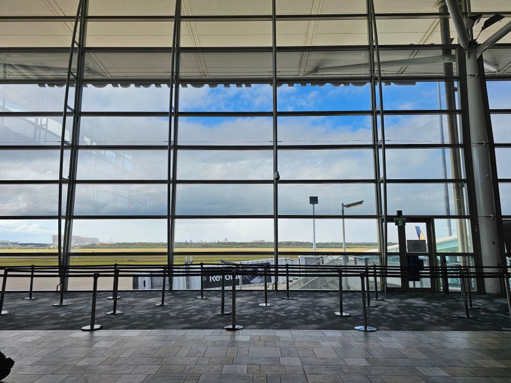 Large airport terminal with floor-to-ceiling windows and a panoramic view of the runway