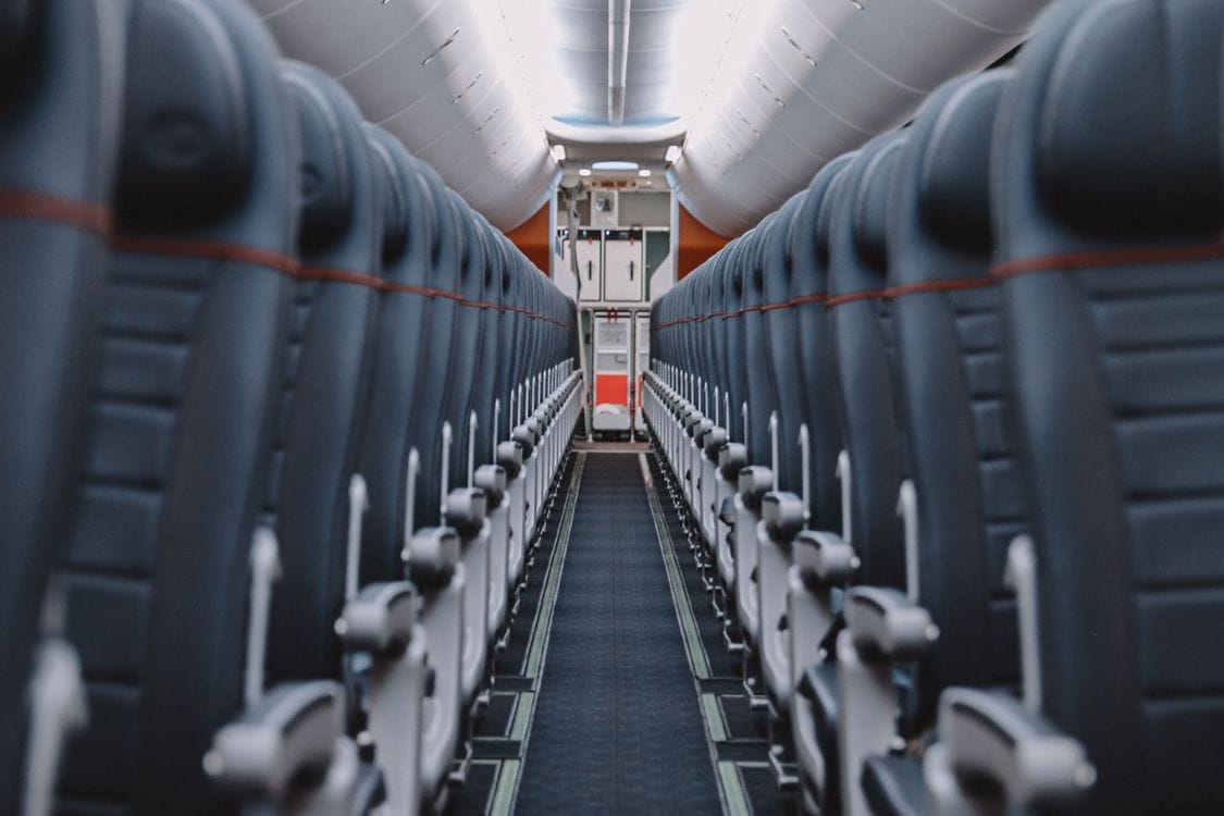 TUI seat selection — view down the aisle of an airplane cabin with overhead compartments