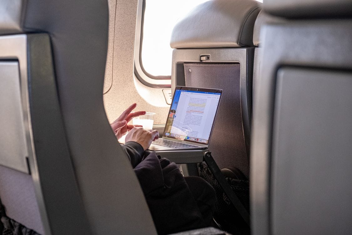 Passenger working on a laptop during a flight, using in-flight WiFi