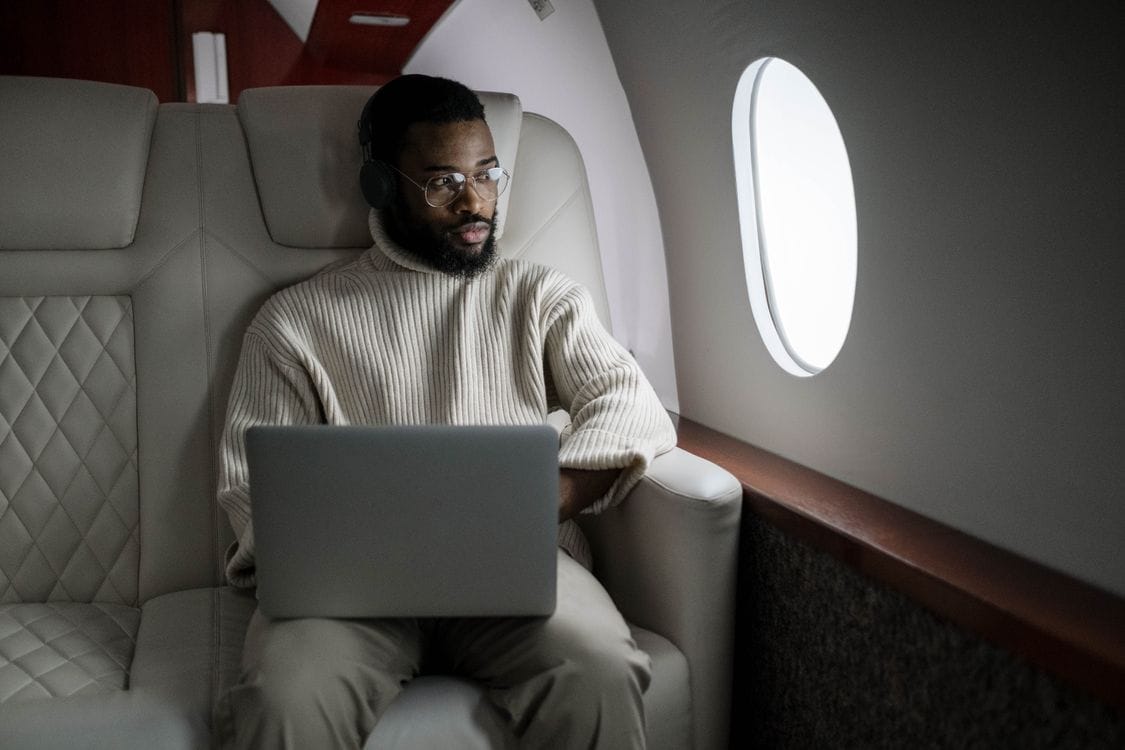 Man wearing headphones using a laptop in a luxurious airplane cabin