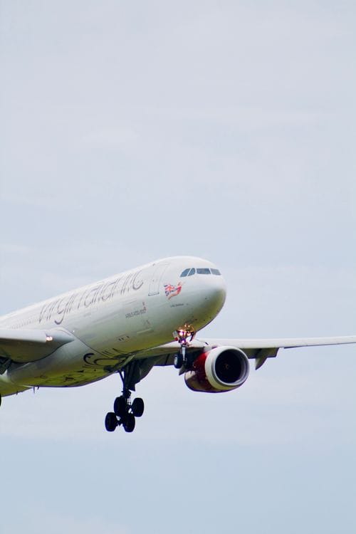 Virgin Atlantic aircraft on final approach to landing with landing gear extended and red engine cowling visible
