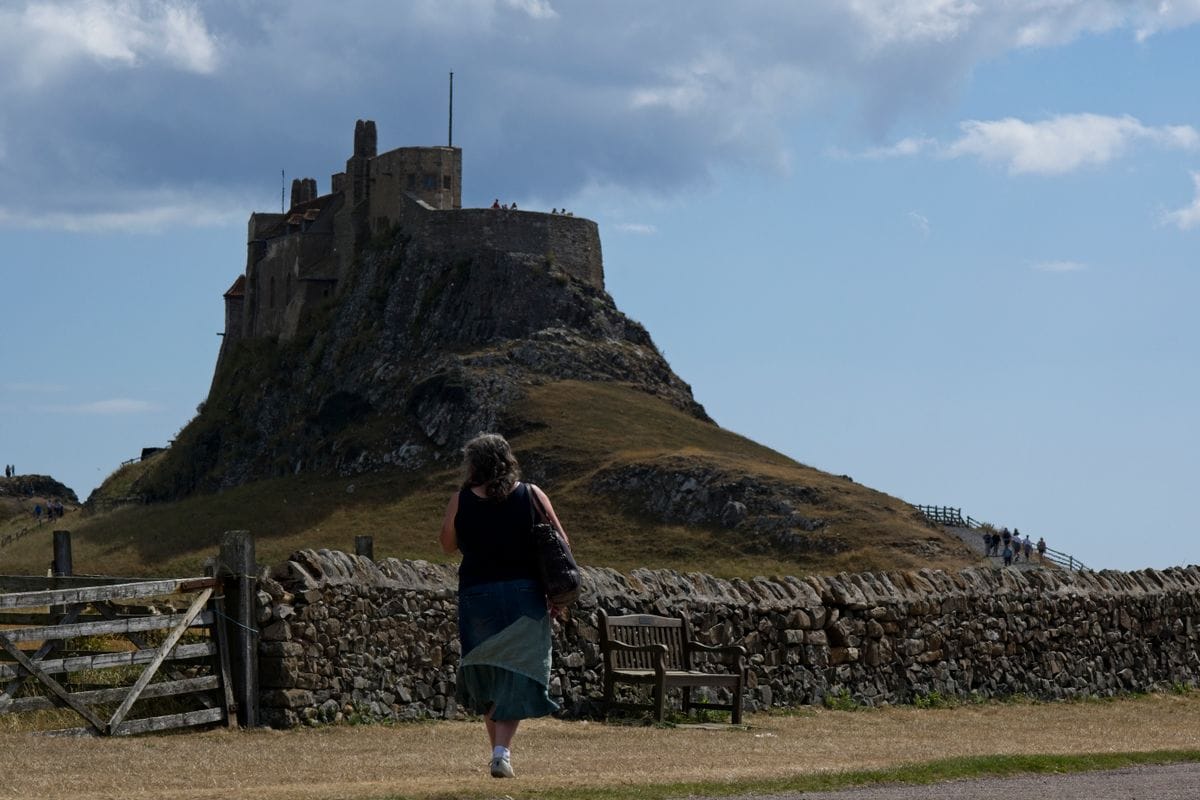 A visitor walks towards Lindisfarne Castle on Holy Island, reachable only at low tide