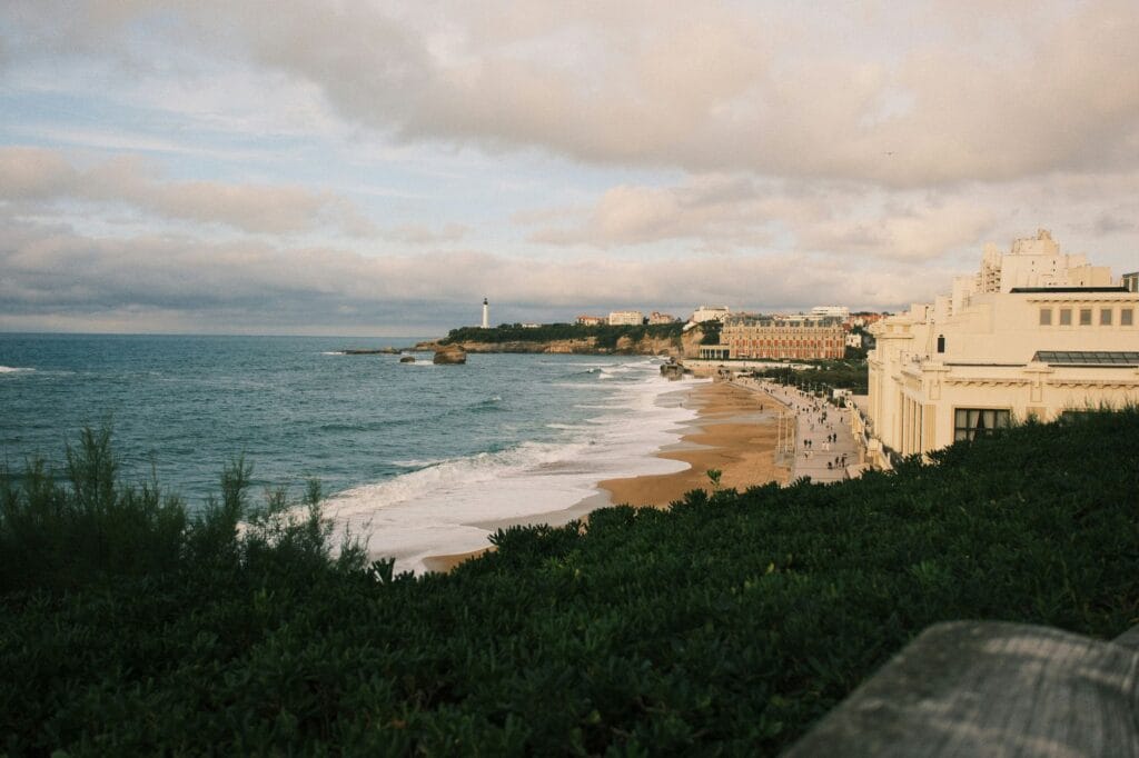 Biarritz on a budget: Grande Plage at dusk with the lighthouse and Hotel du Palais in the distance