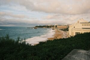 Biarritz on a budget: Grande Plage at dusk with the lighthouse and Hotel du Palais in the distance