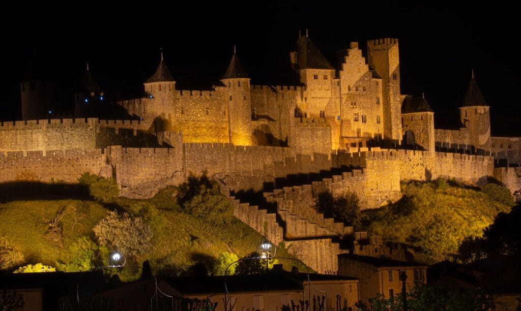 Carcassonne on a budget: the medieval Cite illuminated at night, its towers lit gold against the sky