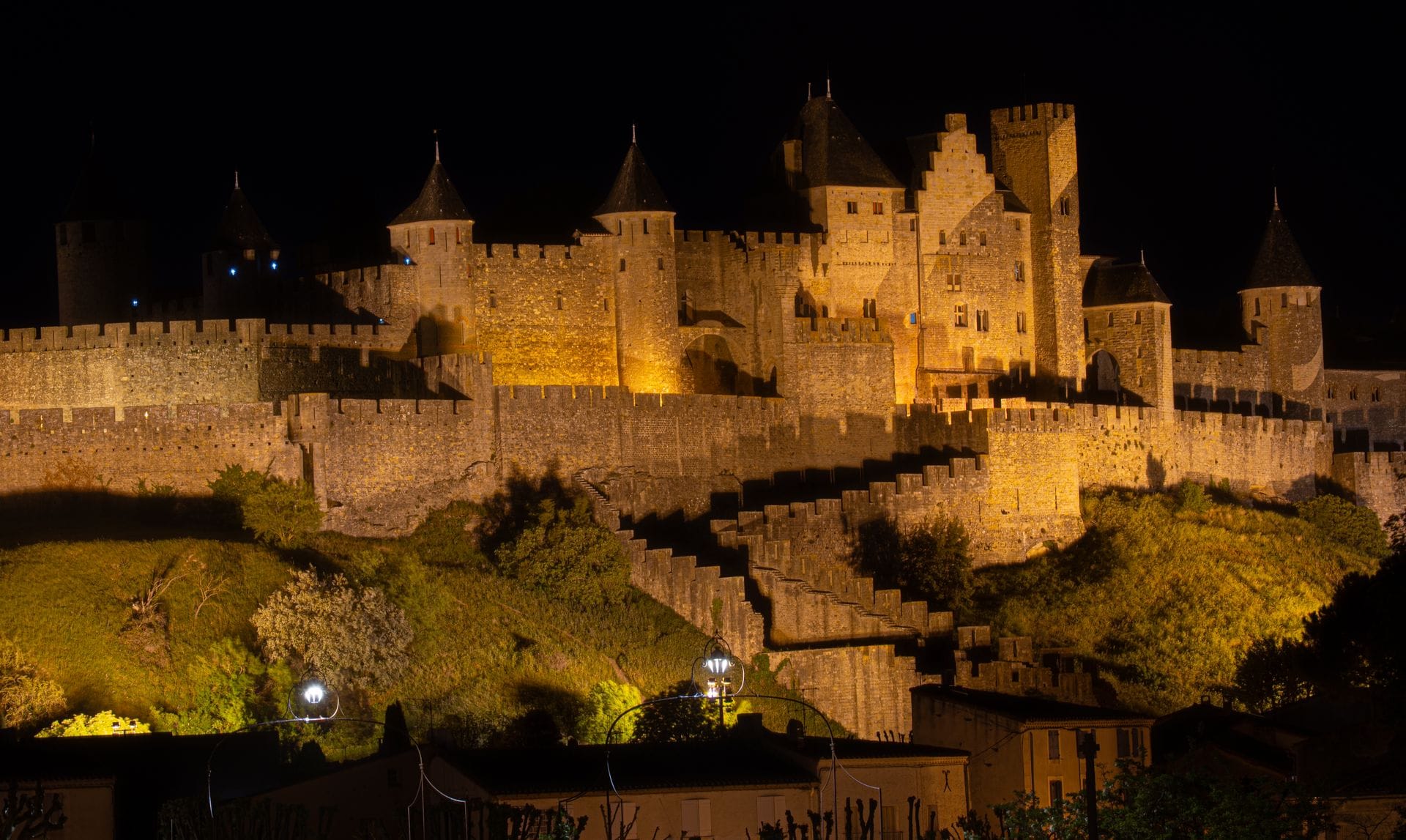 Carcassonne on a budget: the medieval Cite illuminated at night, its towers lit gold against the sky