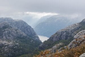 Misty green mountains and a fjord in Norway, representing the coolcations travel trend