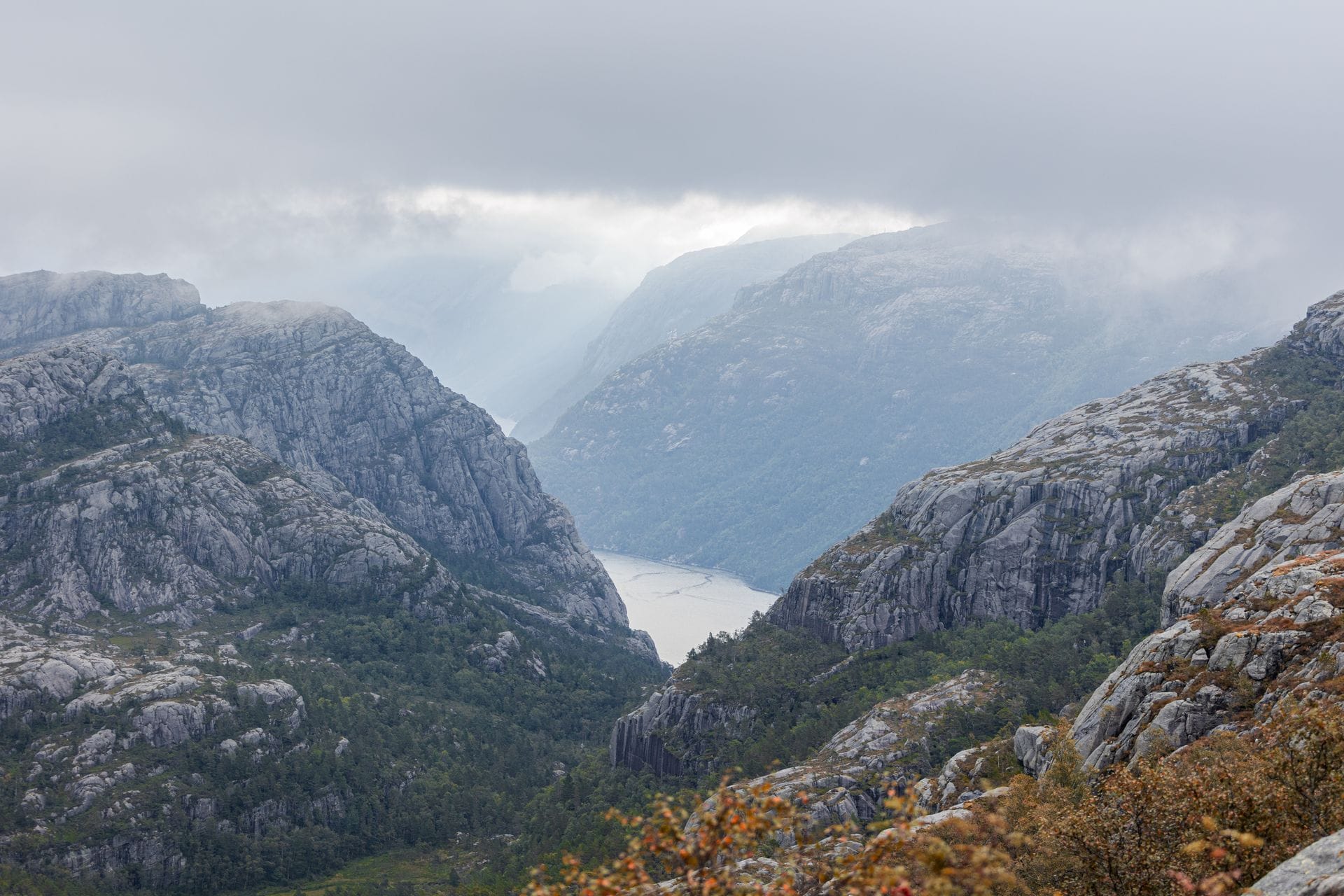 Misty green mountains and a fjord in Norway, representing the coolcations travel trend