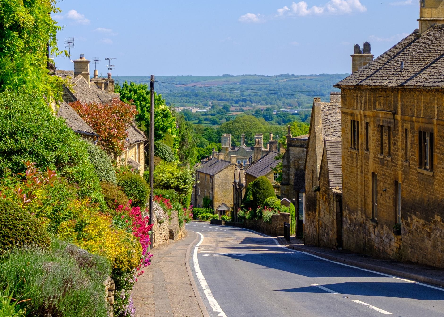 Winding stone-built street in a Cotswold village lined with honey-coloured cottages