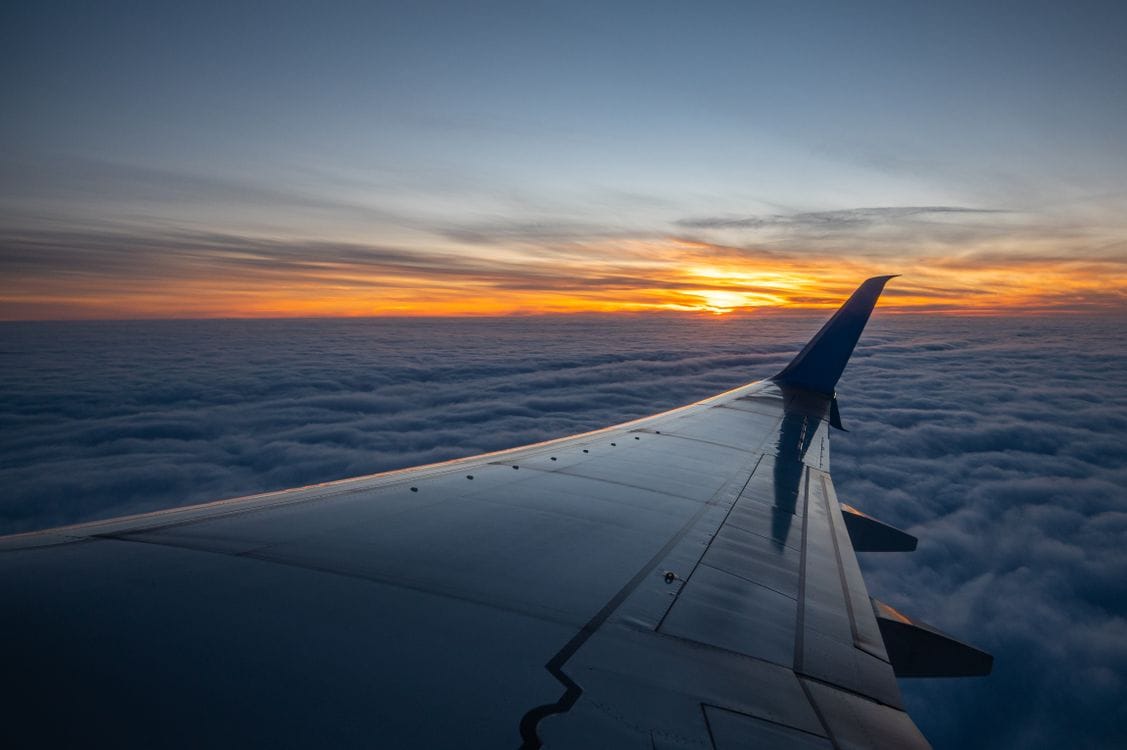 An aircraft wing above the clouds at sunset, representing the hundreds of airlines Expedia packages into its holidays