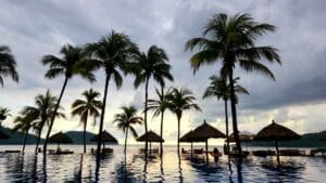 Expedia holidays: sunset at a beach resort infinity pool surrounded by palm trees