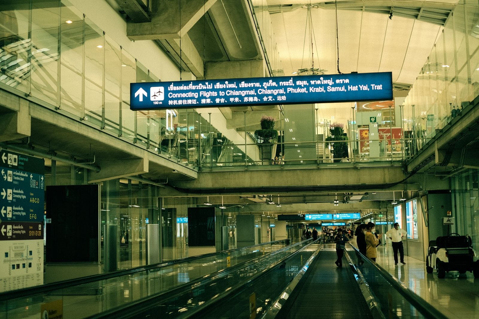 Moving walkway inside Suvarnabhumi Airport, Bangkok, with signs for connecting flights