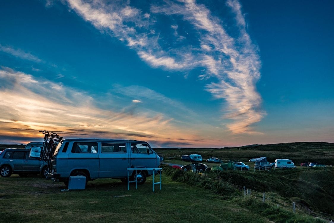 Campervans and tents at a Scottish coastal campsite at dusk