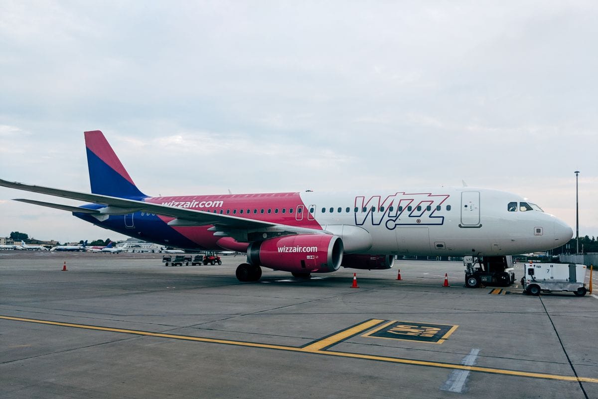 Wizz Air Airbus A320 parked on the tarmac at an airport with ground crew nearby