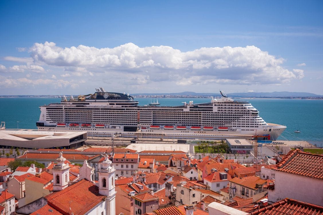 A cruise ship docked at a sunny coastal harbour town