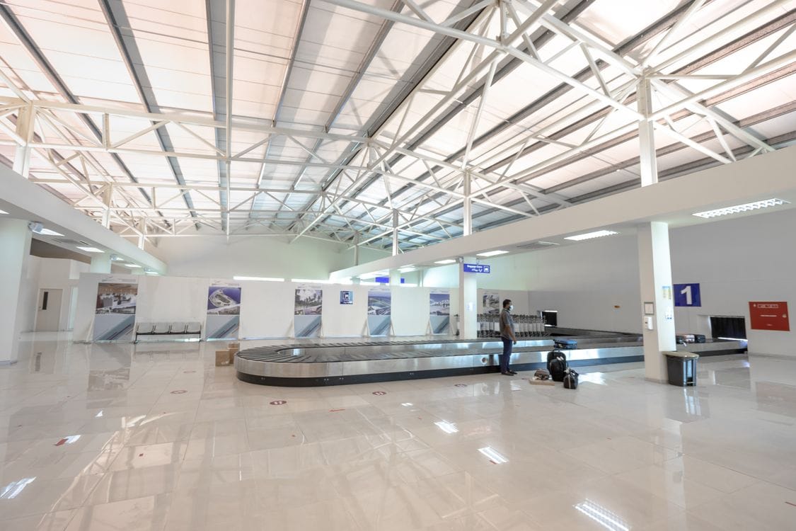 An airport baggage reclaim hall with one traveller waiting beside carousel one