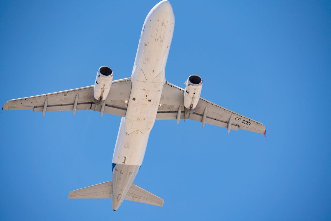 Commercial aircraft climbing into a clear blue sky after departure