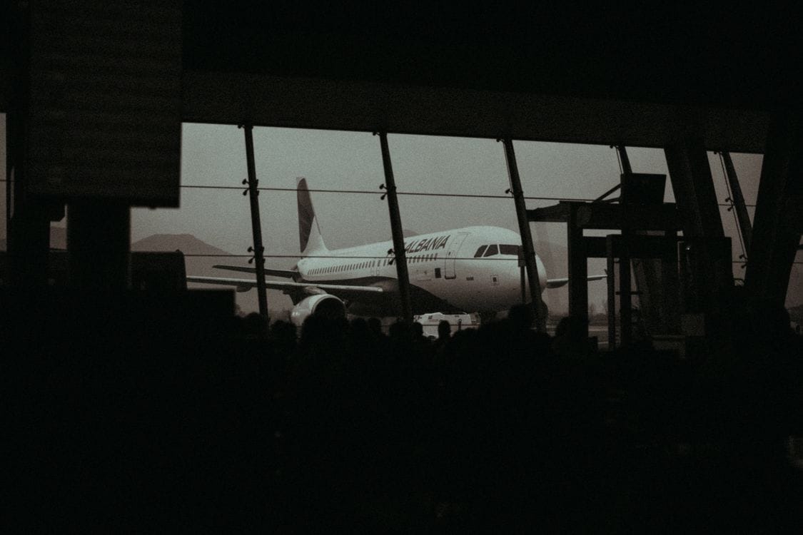 Silhouette of an aircraft and waiting passengers inside an airport departure terminal at dusk