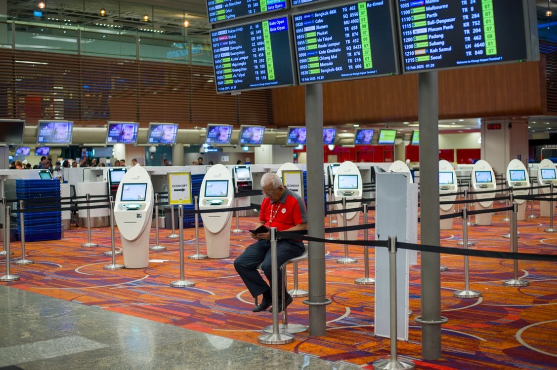 British Airways check in: busy airport terminal interior with flight information displays and check-in kiosks