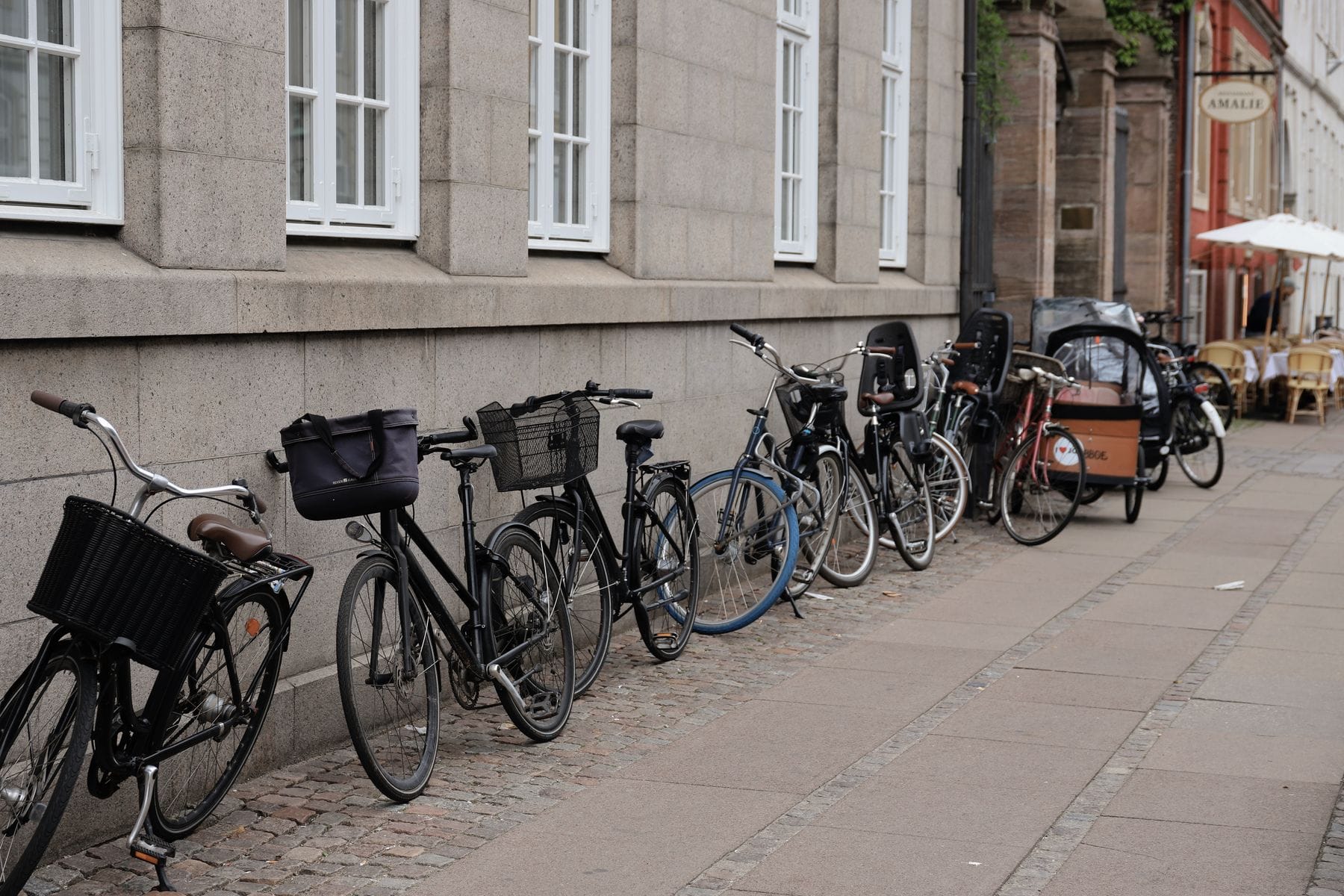 A row of bicycles, including a cargo bike, parked along a Copenhagen street