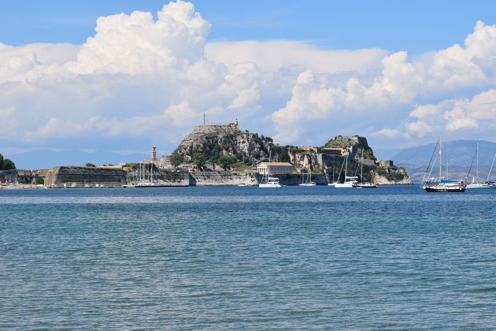 Is Corfu expensive: the Old Fortress of Corfu on its headland across the water, with sailing boats moored in front