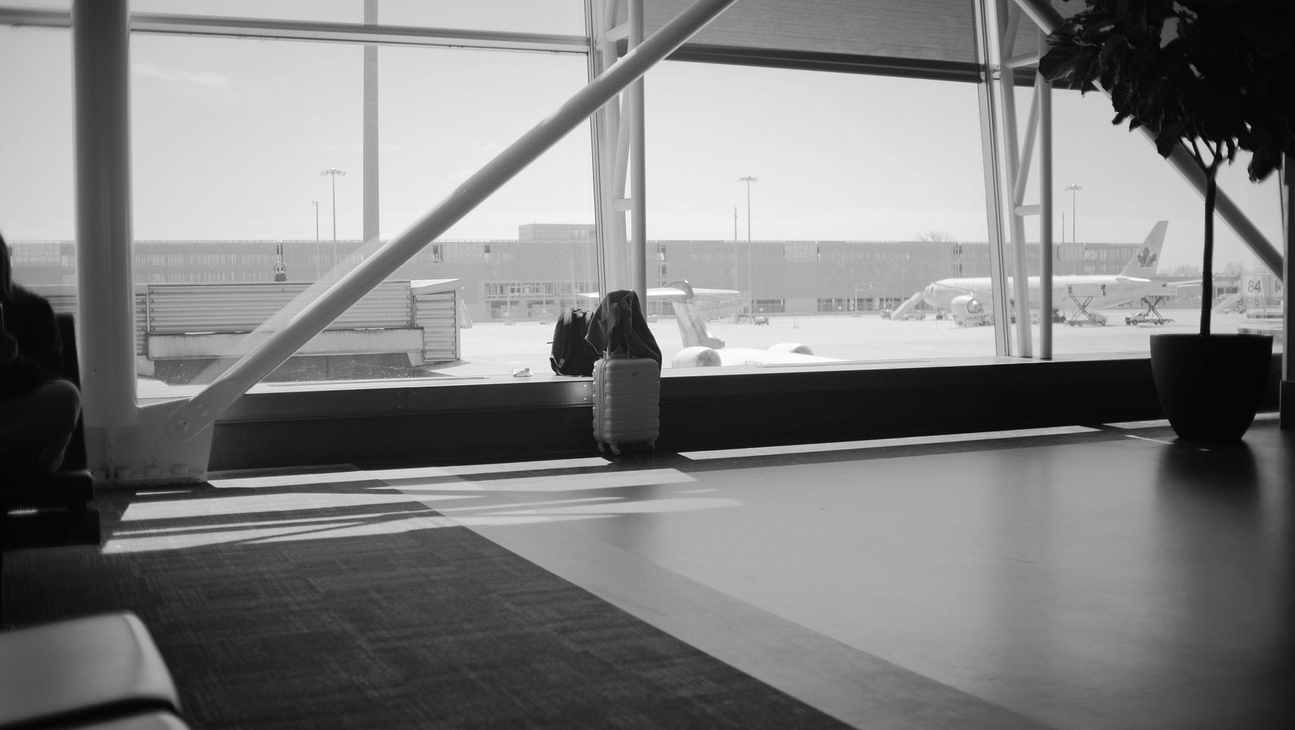 Suitcase by an airport lounge window overlooking the runway and aircraft