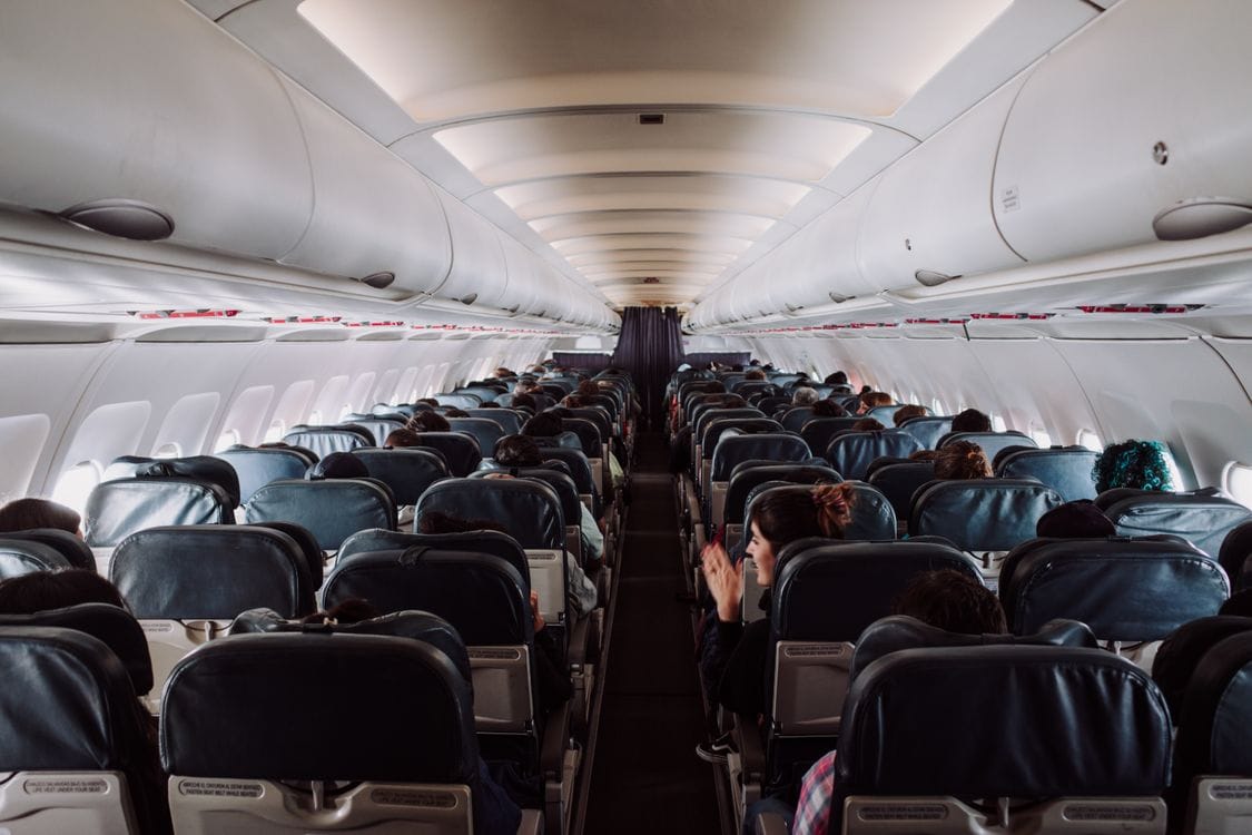 Rows of airline passenger seats and overhead lockers inside an aircraft cabin