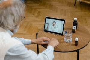 Goodtogoinsurance reviews: an older man on a video call with a doctor, the kind of medical history this travel insurance specialist screens for