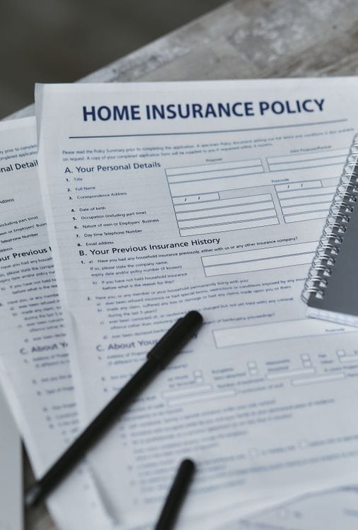 A flatlay of an insurance policy document and notebook on a desk