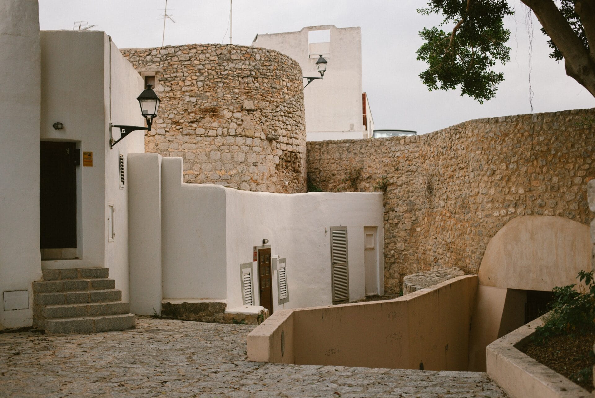 Rustic stone fortress walls and a whitewashed alley inside Ibiza's Dalt Vila old town
