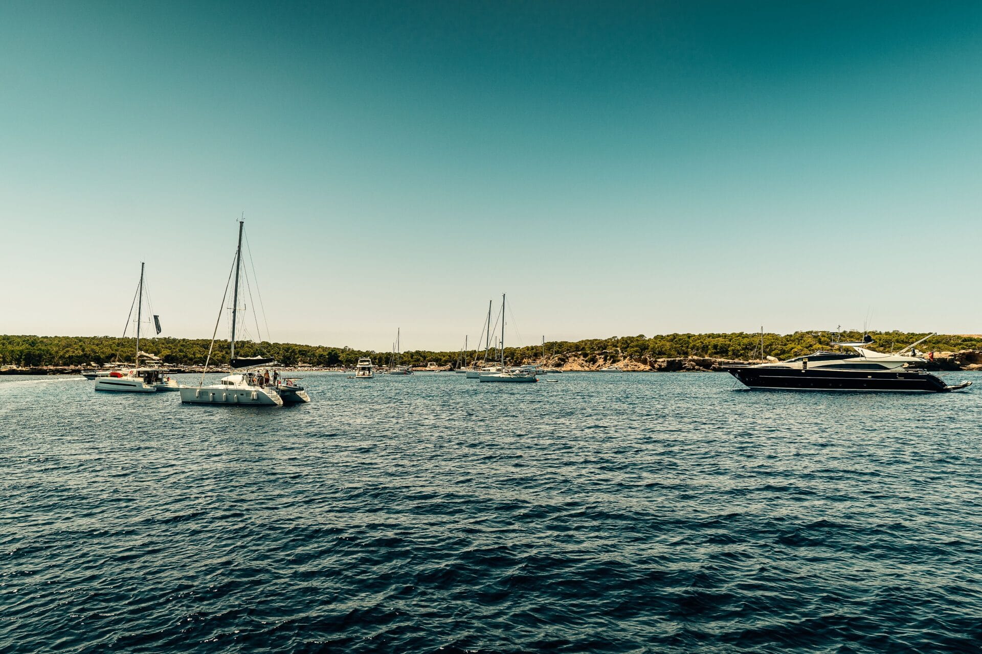 Sailboats and yachts anchored in a bay off the Ibiza coastline
