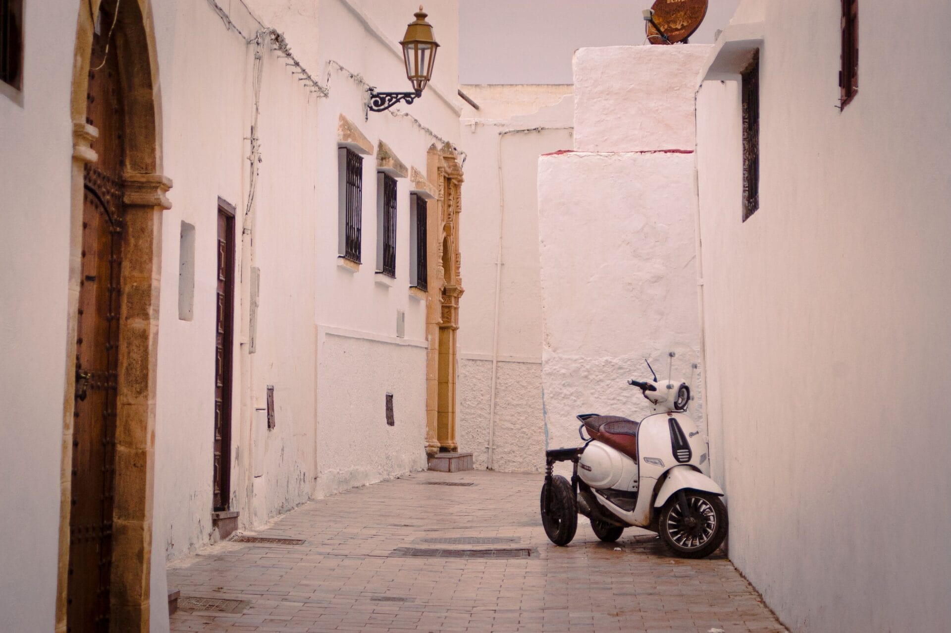 A scooter parked in a narrow whitewashed alley in Ibiza's old town