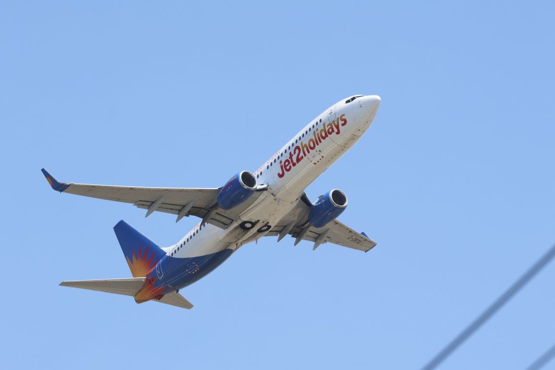 A Jet2holidays aircraft climbing against a clear blue sky shortly after take-off