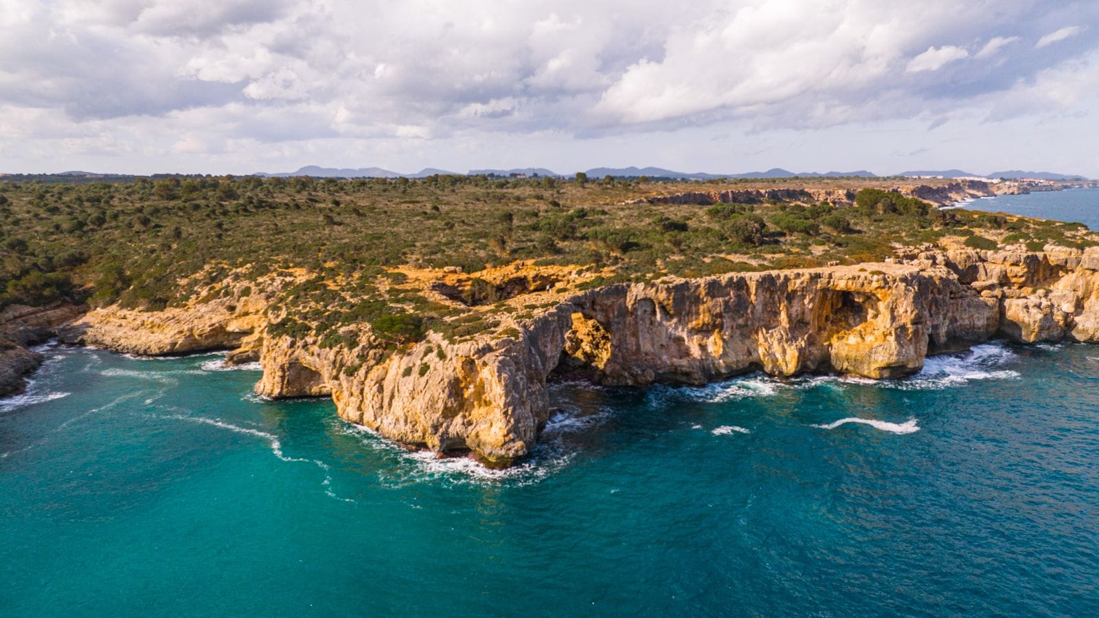 Aerial view of cliffs and a turquoise cove on Majorca's coastline