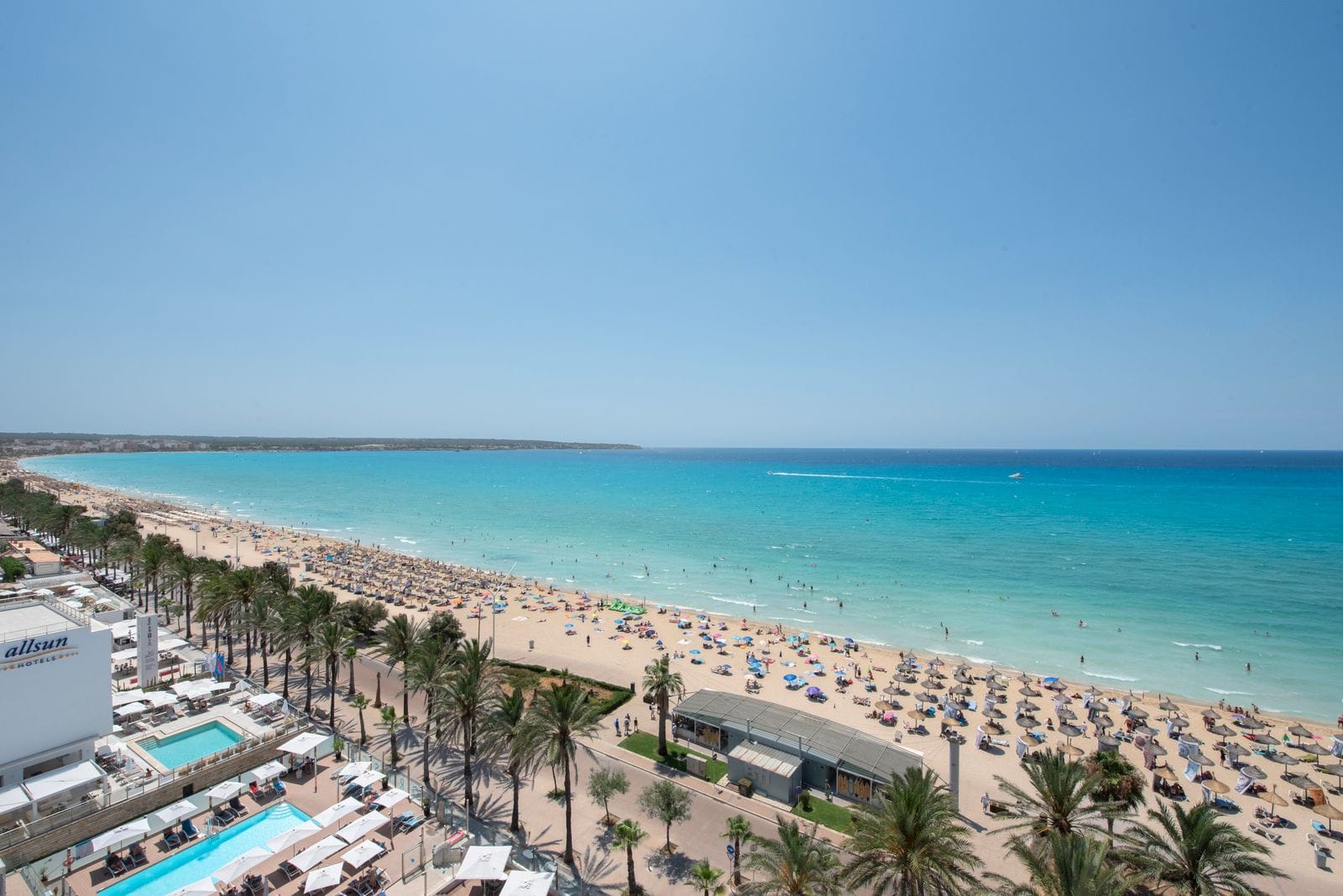A sunny resort beach on the Majorca coastline with sunbeds along the shore