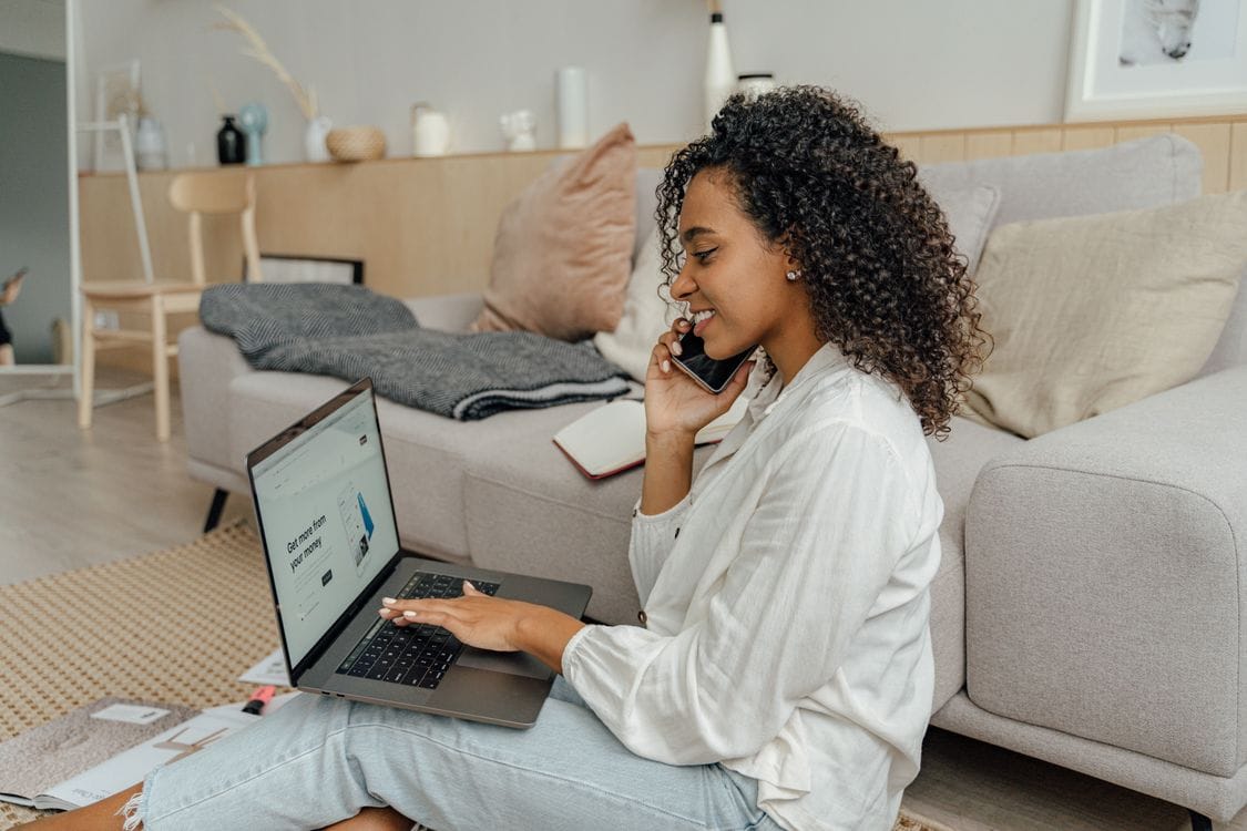 A woman managing a booking on a laptop while on the phone, similar to cancelling a British Airways flight in Manage My Booking