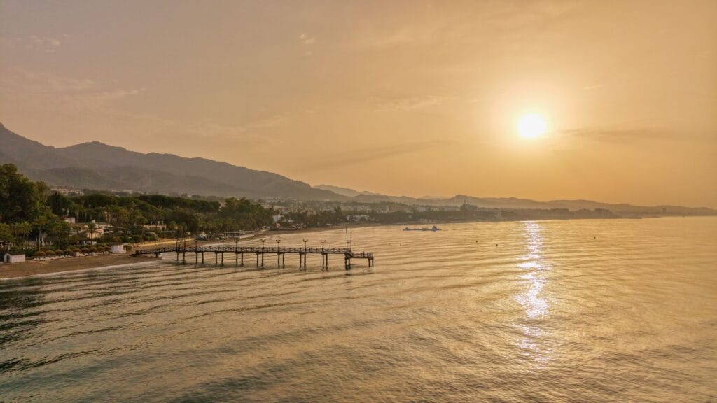 Marbella on a budget: sunset over Marbella coastline and pier on the Costa del Sol