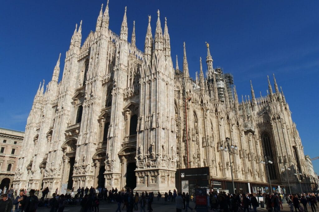 Is Milan worth visiting: the Gothic marble facade of Milan's Duomo cathedral against a clear blue sky